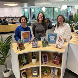 Three librarians stand next to the new World Languages Collection shelf